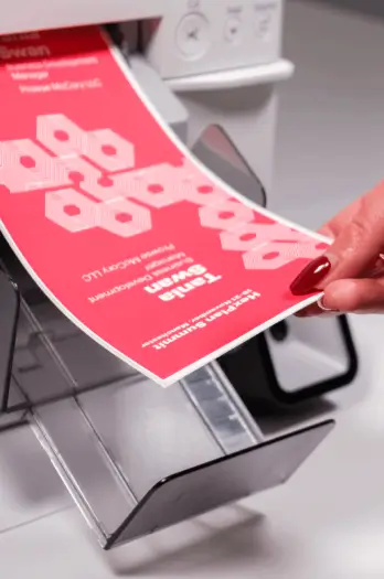 lady's hand holding onto a badge being printed from a badge printer