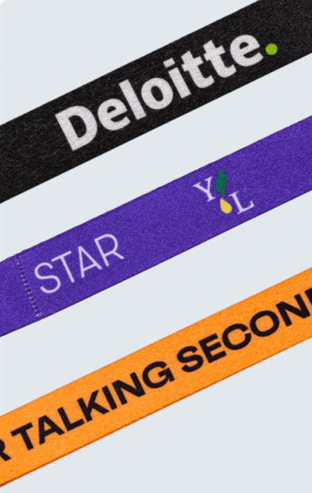 Three branded lanyards laid diagonally on a brown background: a black lanyard with the white Deloitte logo, a purple “STAR” lanyard, and an orange lanyard reading “I PREFER TALKING SECOND” with small icon graphics at each end.