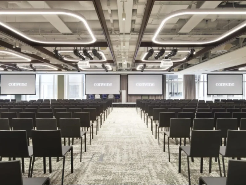 Spacious conference room with rows of chairs and large screens
